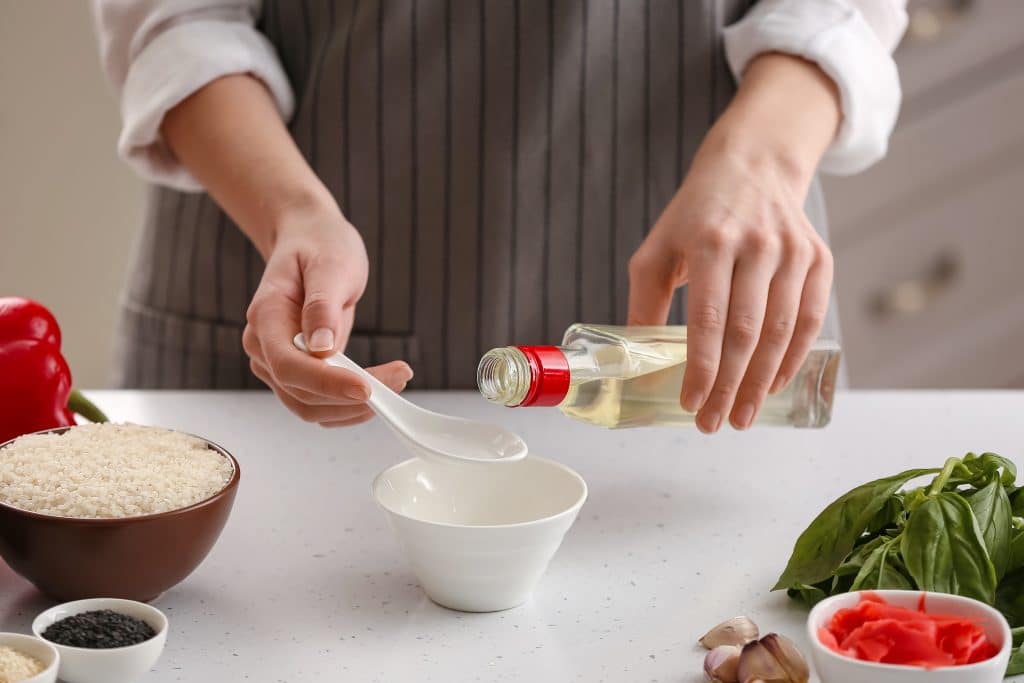 Woman preparing sauce with rice vinegar in kitchen